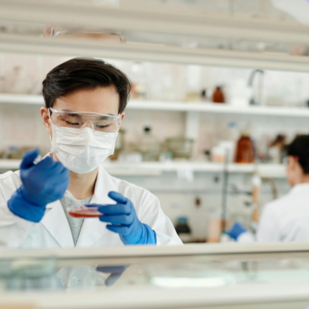 A researcher in a laboratory using protective gear and handling samples, representing data-driven medical research.