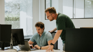 Two team members at Griffith Foods working together on a laptop, discussing data on the screen in a modern office setting.