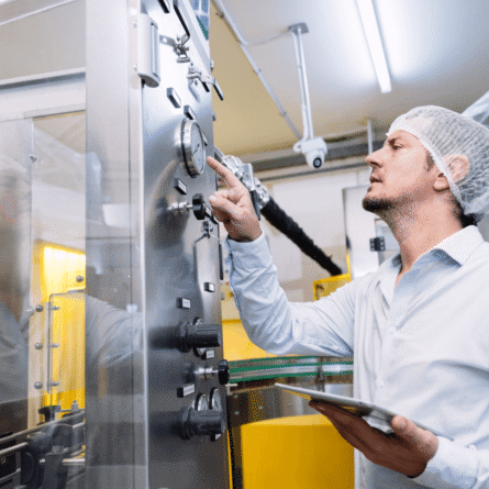 Engineer Adjusting Machine In Food Manufacturing Facility And Pointing Finger At Machine