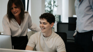 A team of Mercedes-Benz employees collaborating and discussing a project while looking at a computer screen.