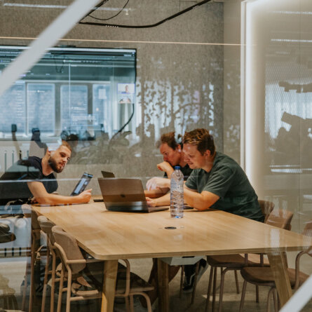 Team members at Hyperion engaging in an automation and integration strategy meeting, collaborating with laptops and a tablet in a modern conference room.