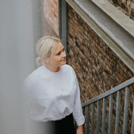 A woman in a white shirt standing on a staircase, reflecting on marketing strategies in a creative office environment.